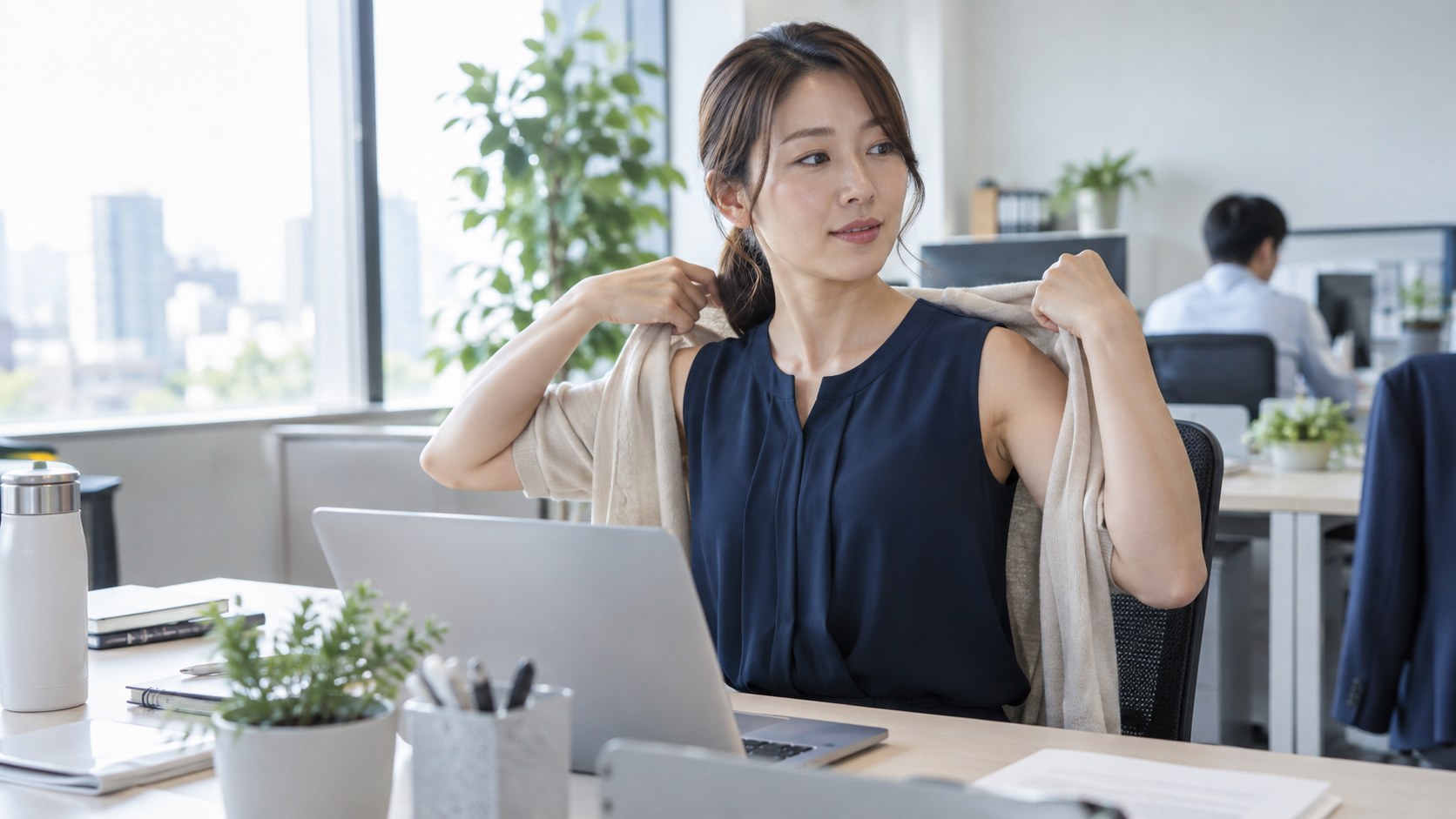 ノースリーブの服に羽織りを合わせて働く女性