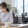 オフィスで仕事に集中する女性と離れた場所の同僚