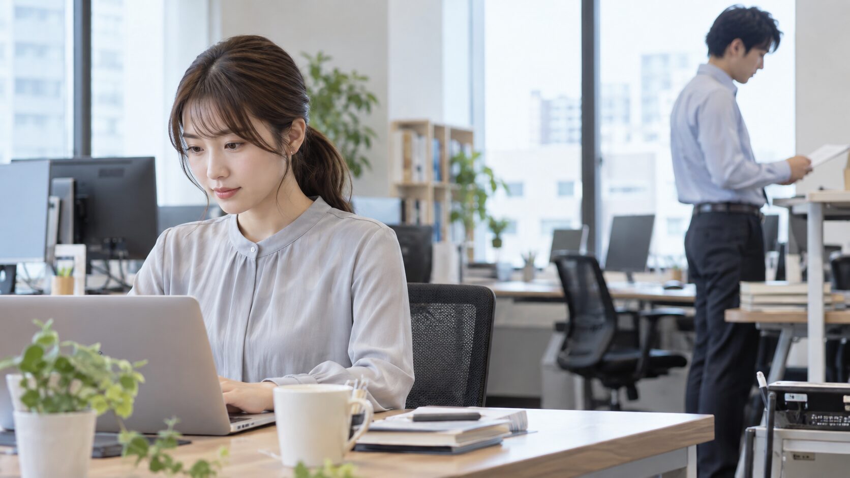 オフィスで仕事に集中する女性と離れた場所の同僚