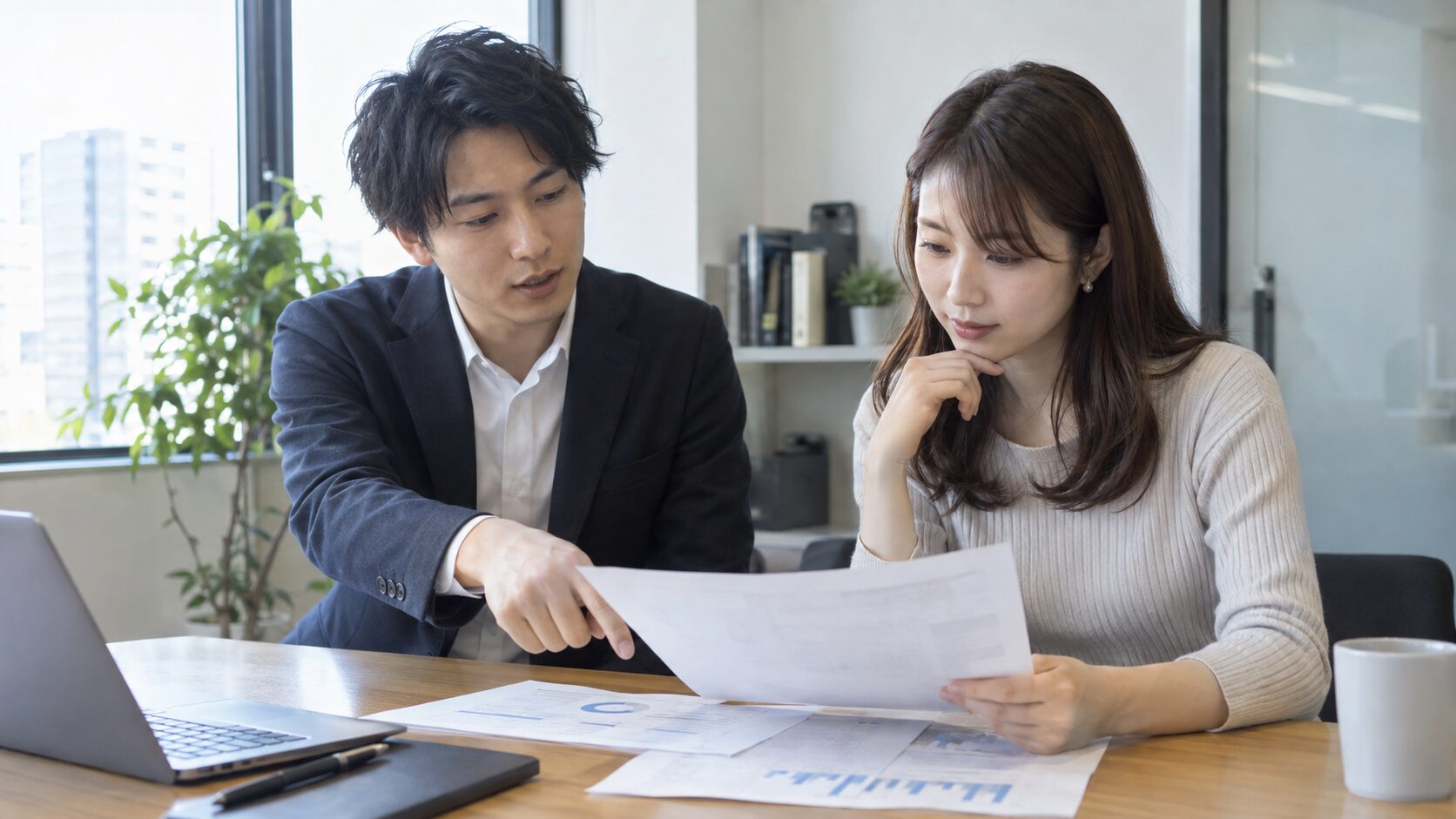 会議室で書類を確認しながら落ち着いて話す男女の同僚