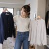クローゼットでカーディガンとブラウスを見比べる女性