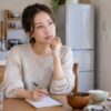 自宅で食事と体調についてメモする女性のイメージ