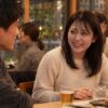飲食店で男性の友人と会話する成人女性