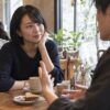 カフェで男性の話を穏やかな表情で聞く成人女性