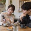 カフェで行きたい場所の写真を男性に見せる女性