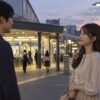 夕方の駅前で男性を気遣って見送る女性