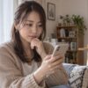 自宅で男性からのメッセージを確認する女性