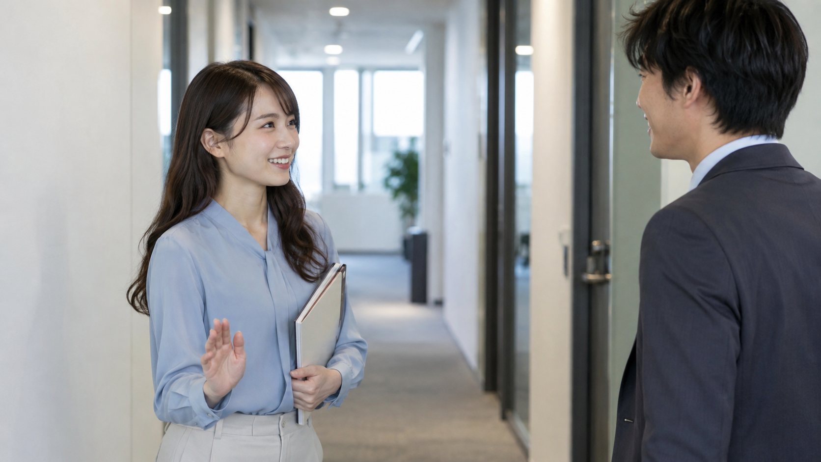 職場の廊下で低い位置から小さく手を振って挨拶する女性