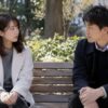 公園のベンチで距離を保ち、真剣に話す男女