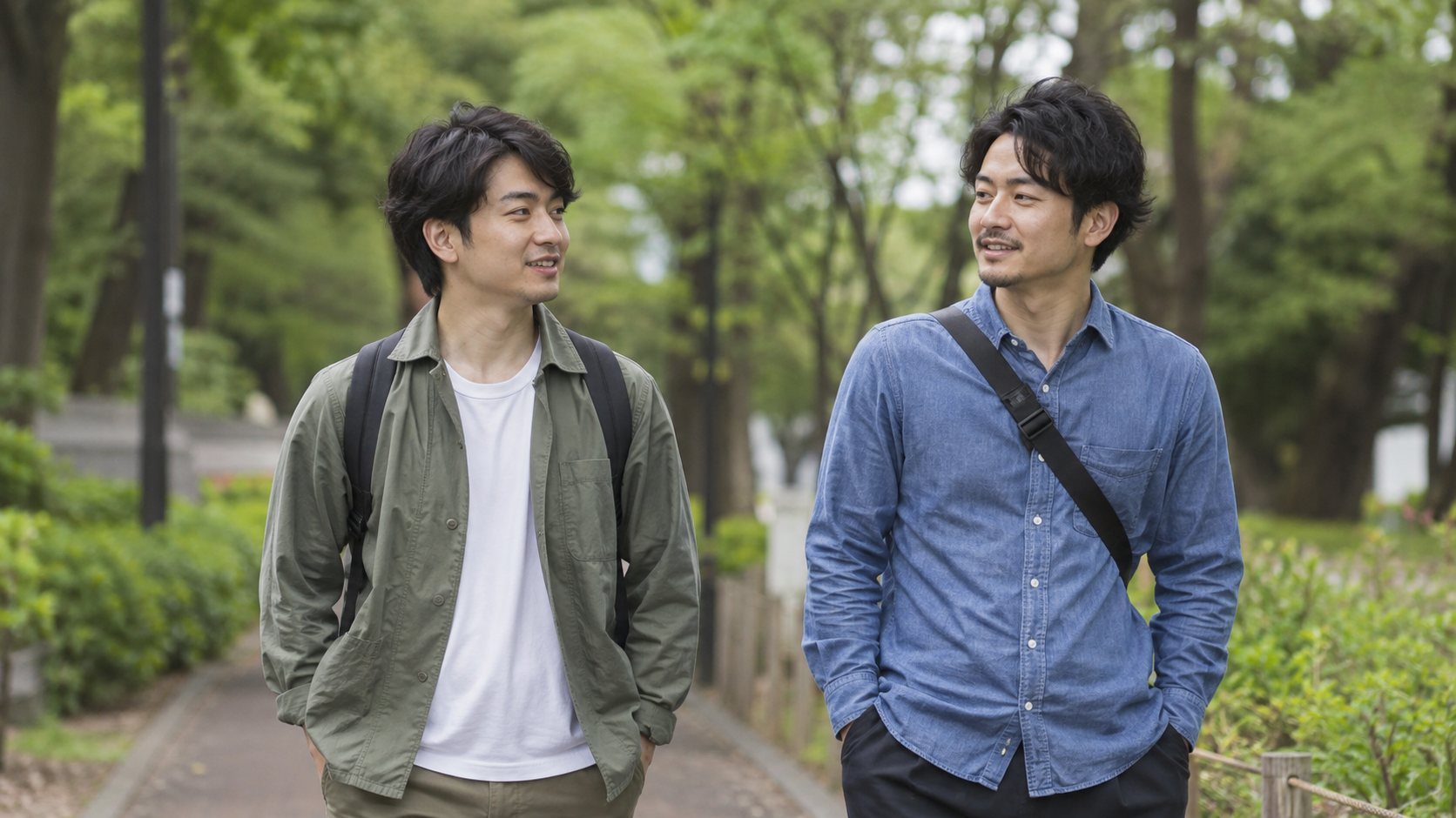 緑の多い道を友人と歩きながら話す男性たち