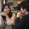 カフェで男性と話しながら笑顔を見せる女性