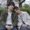 ベンチで男性の肩にそっと頭を乗せる成人女性