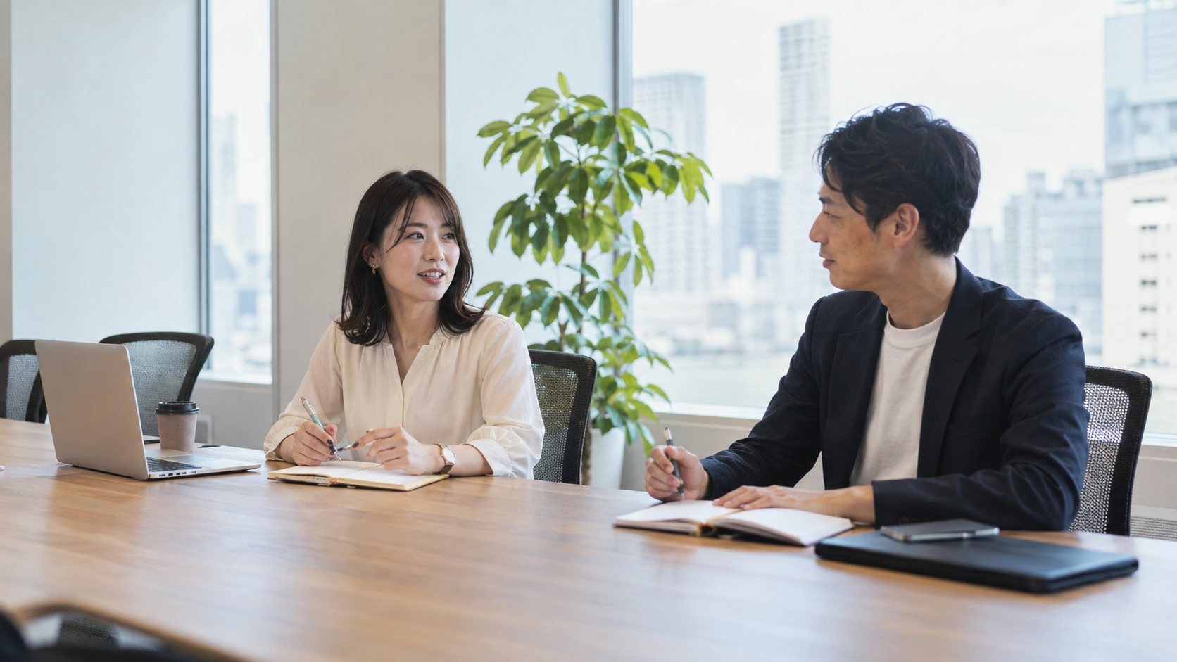 会議用の机で適度な距離を保ち、話をする男女の同僚