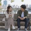 公園のベンチで横並びに座って話す成人の男女