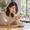 カフェの窓辺でスマートフォンを確認する女性