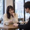 カフェで男性の手に目を向ける女性