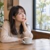 カフェの窓際で落ち着いて考える女性