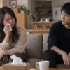 涙を拭く女性を少し離れて見守る男性